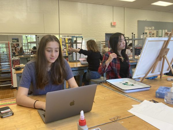 One class, yet two different mediums collide. Nex Thompson edits their photos next to fellow AP art student Joy Wei painting a piece for her portfolio. 