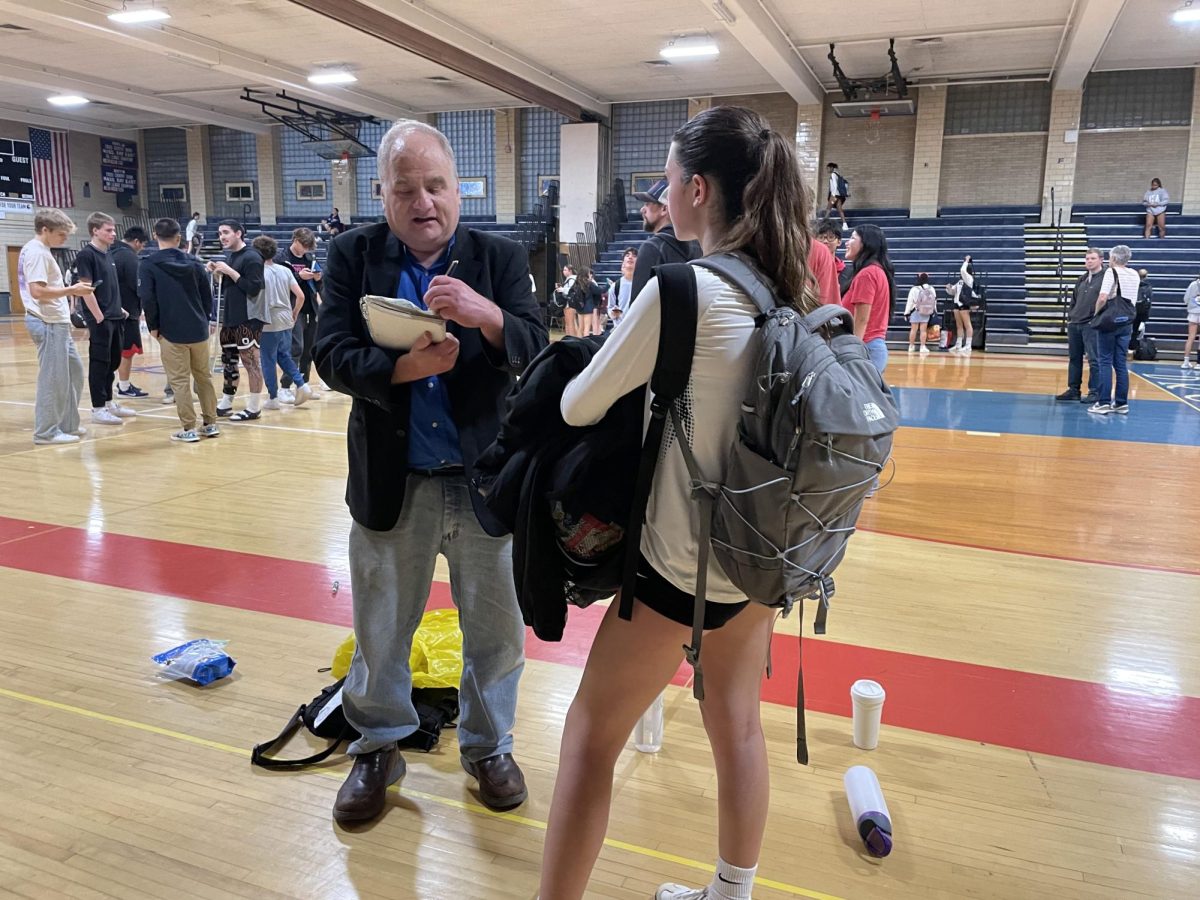 Eliot Schickler conducts an interview after the girls varsity volleyball team’s 3-0 win against the Bos-
ton Latin School Wolfpack on Thursday, Sep. 26 in the Schluntz Gymnasium.