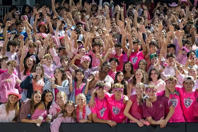 Students cheer in the fan section of a varsity football game with a theme of pink out for breast cancer
awareness.