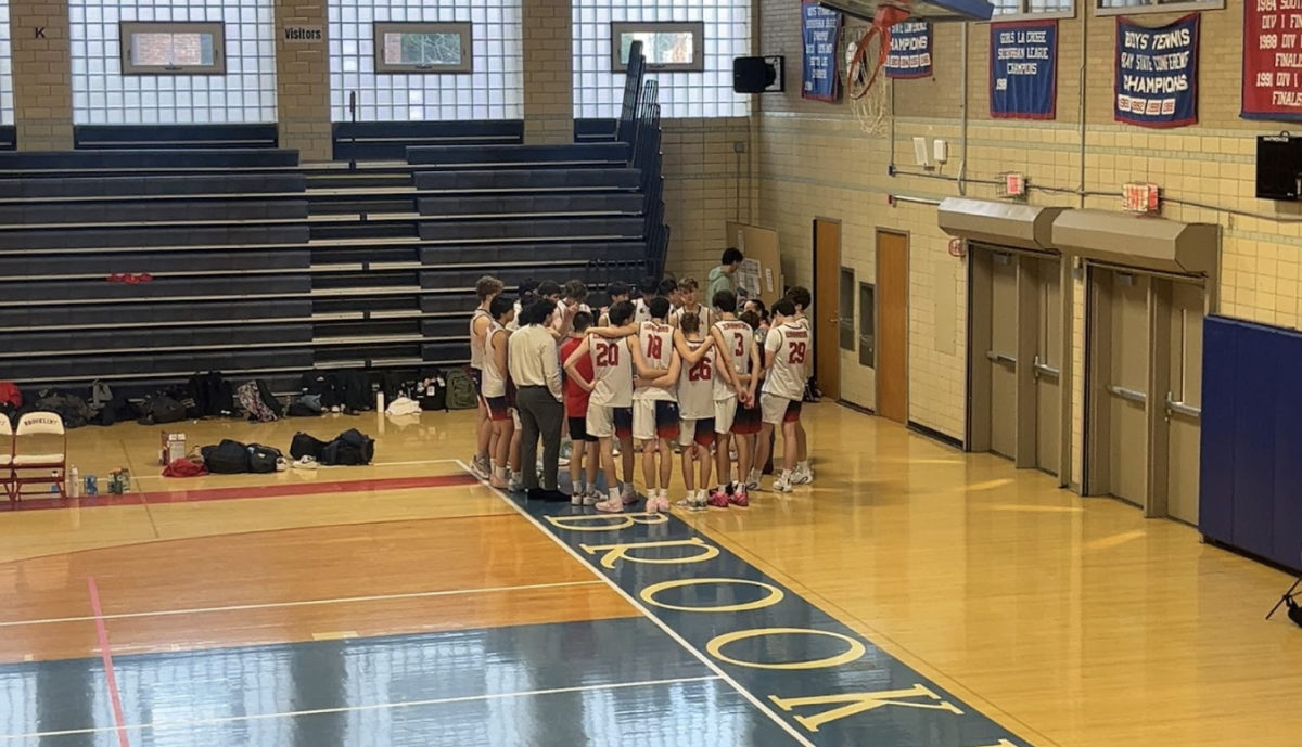 The boys varsity volleyball team huddles together in their recent game against the Wellesley Raiders. This season, having a good mentality has been important to the team's sucess.